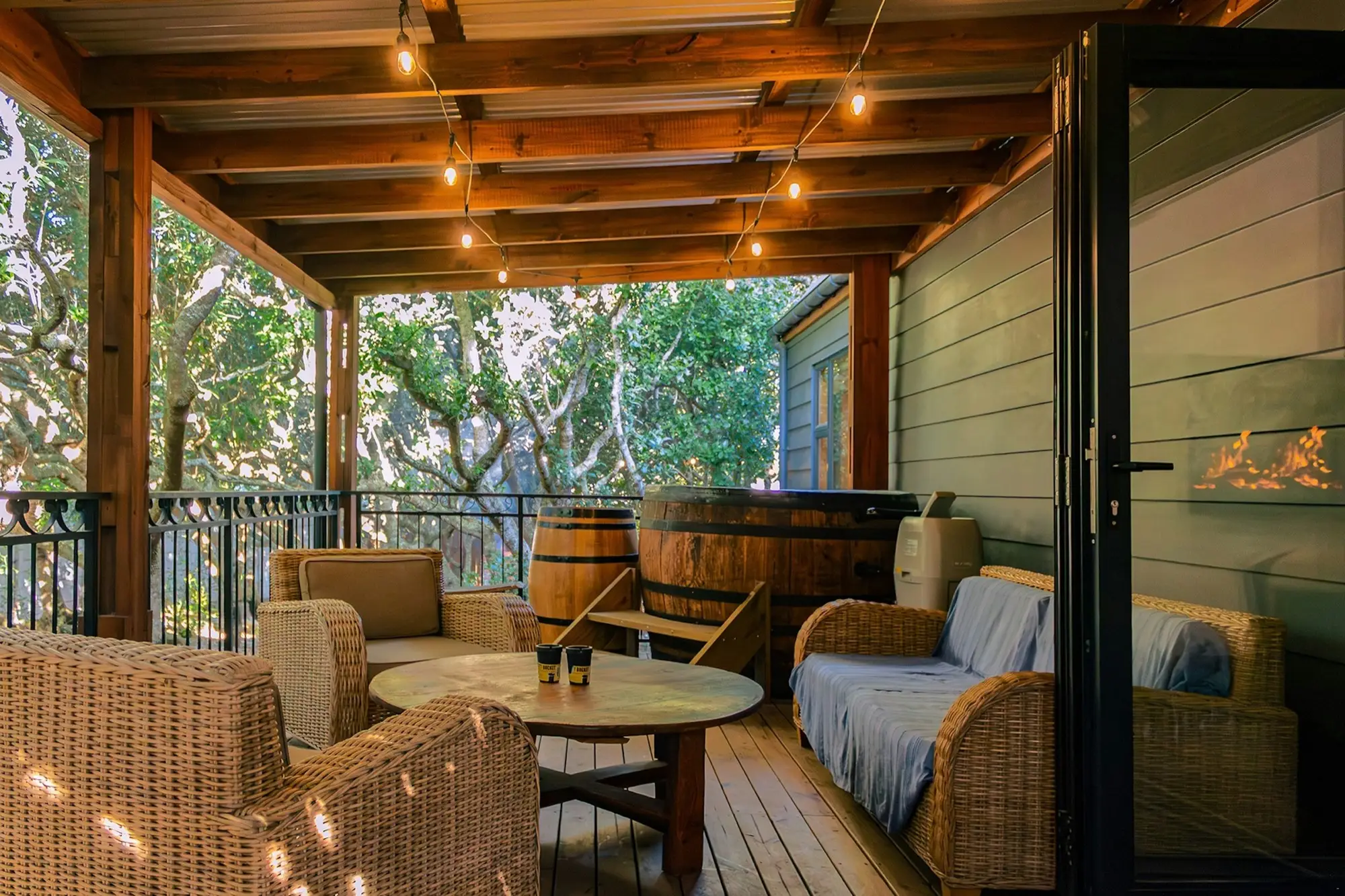 The hot tub on the covered deck, with wicker armchairs and festoon lights