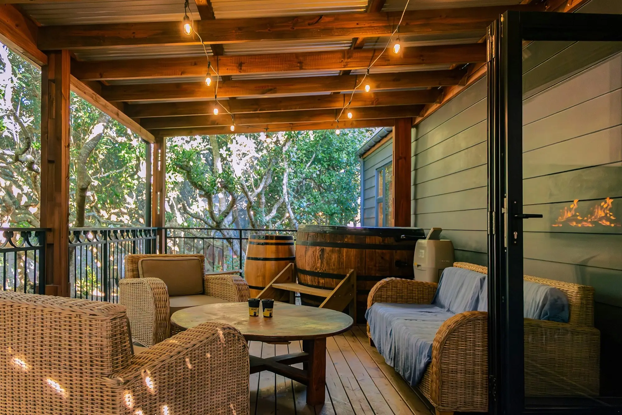 The hot tub on the covered deck, with wicker armchairs and festoon lights