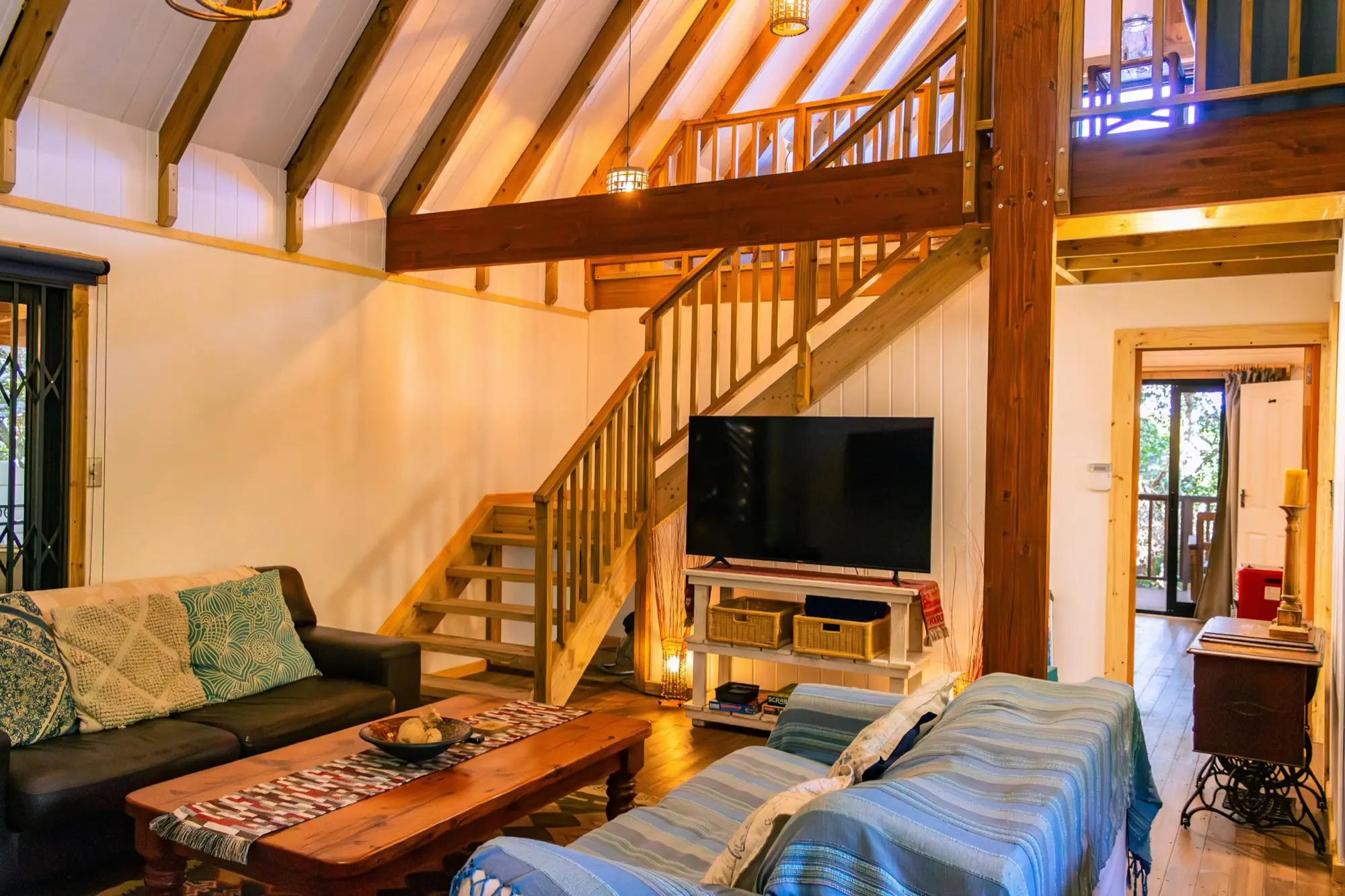 Living room looking up to the loft, with a timber staircase and exposed beams