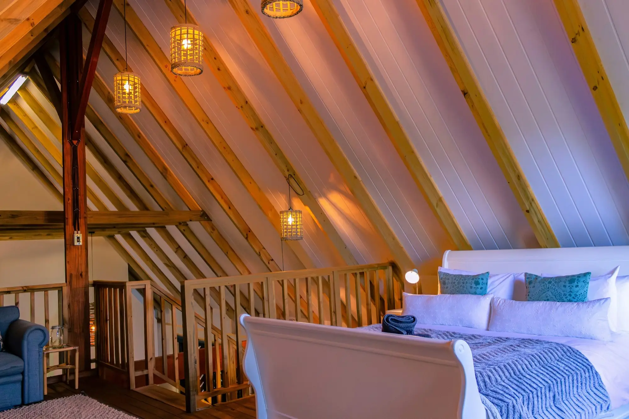 Loft bedroom under the A-frame rafters with pendant lights and a sleigh bed