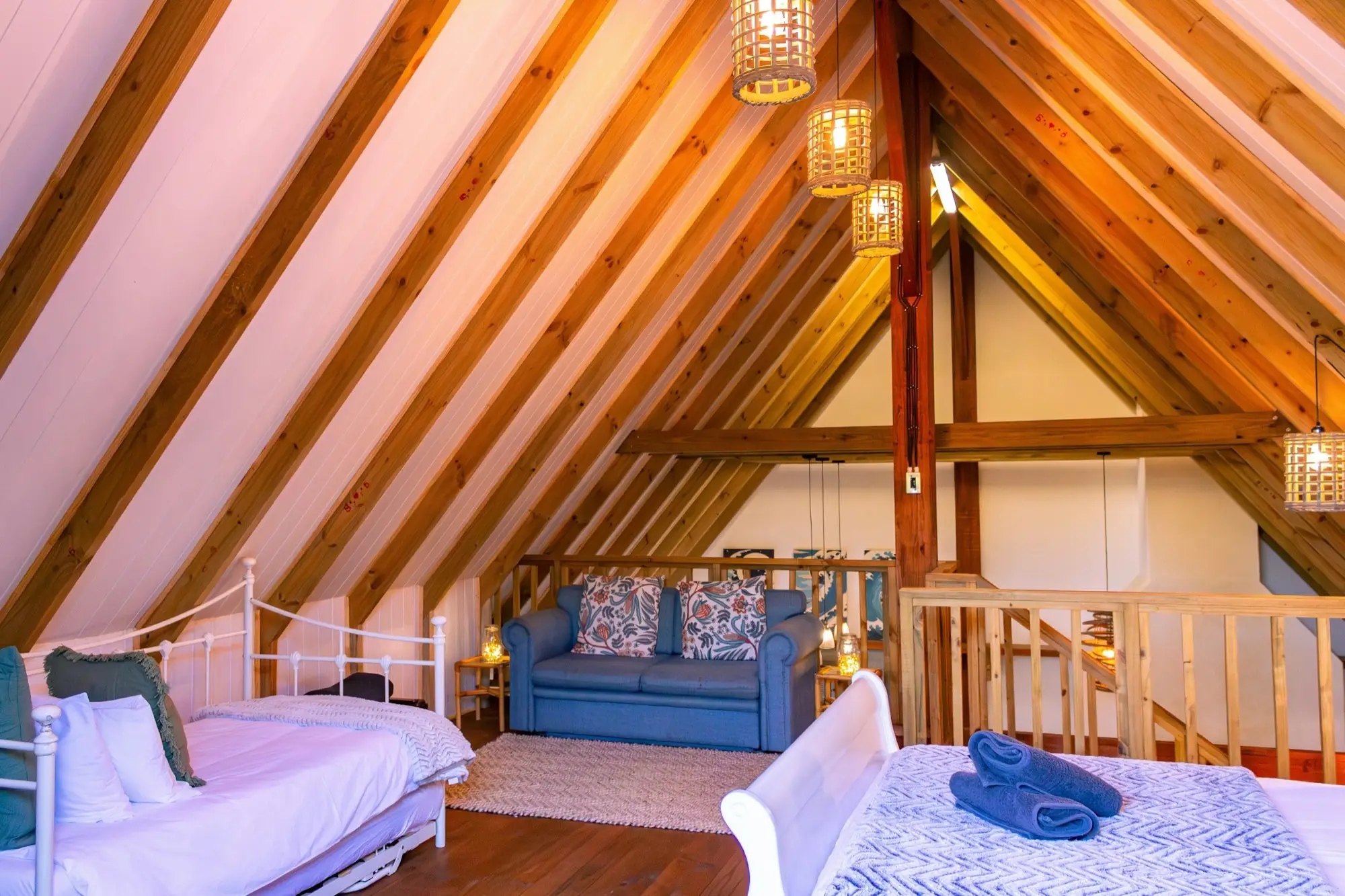 Sitting area in the loft with a sofa between two beds under the rafters