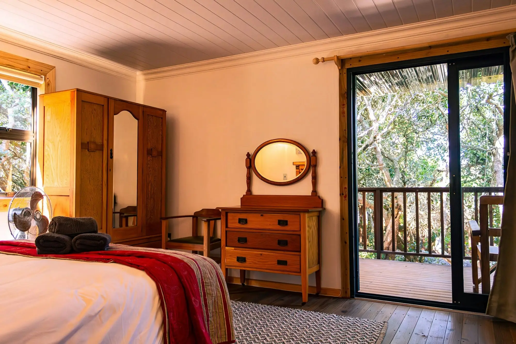 Master bedroom with an antique dresser and a glass door onto the deck