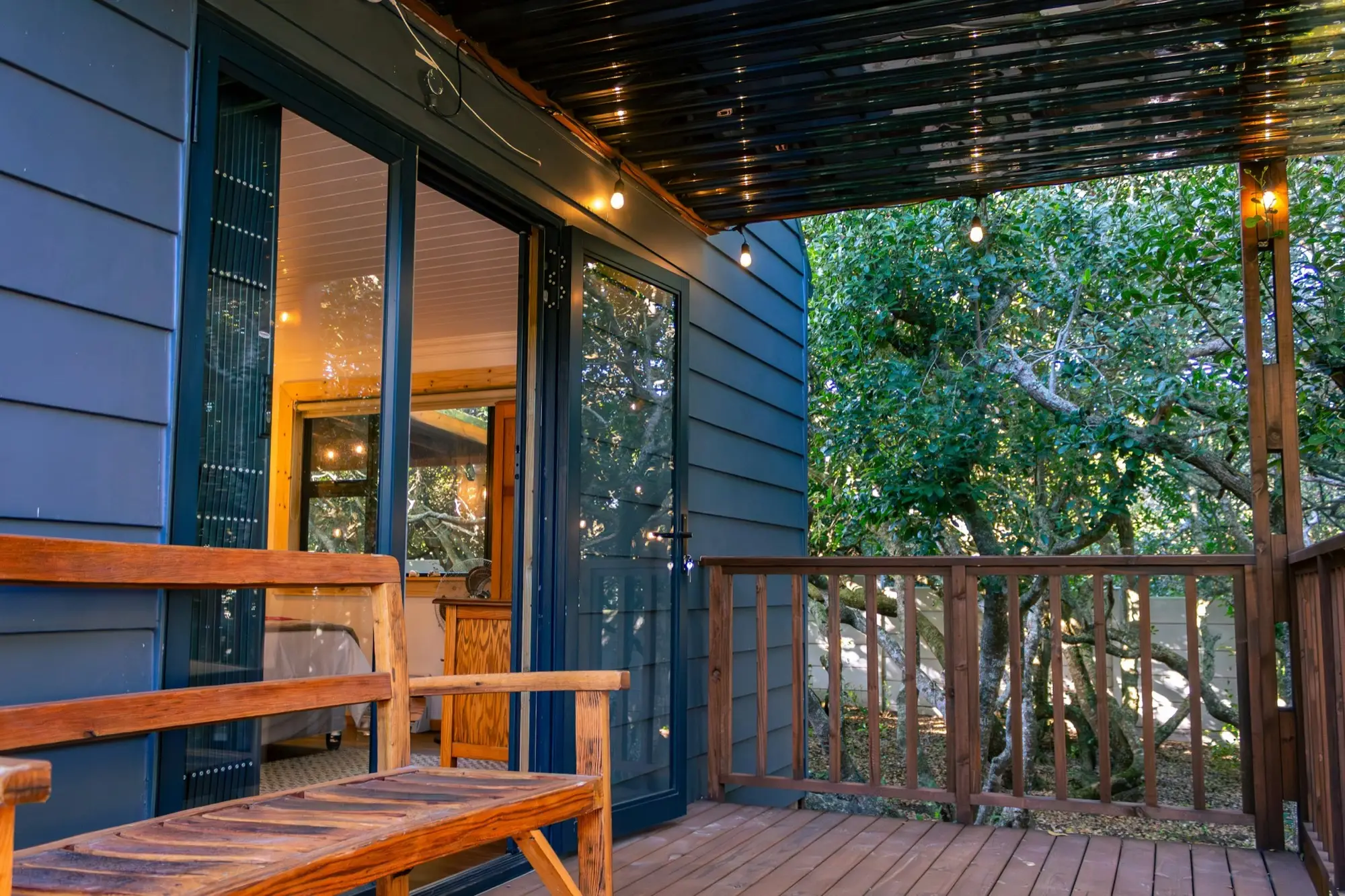 Timber bench and sliding doors at the deck entrance, lit by string lights