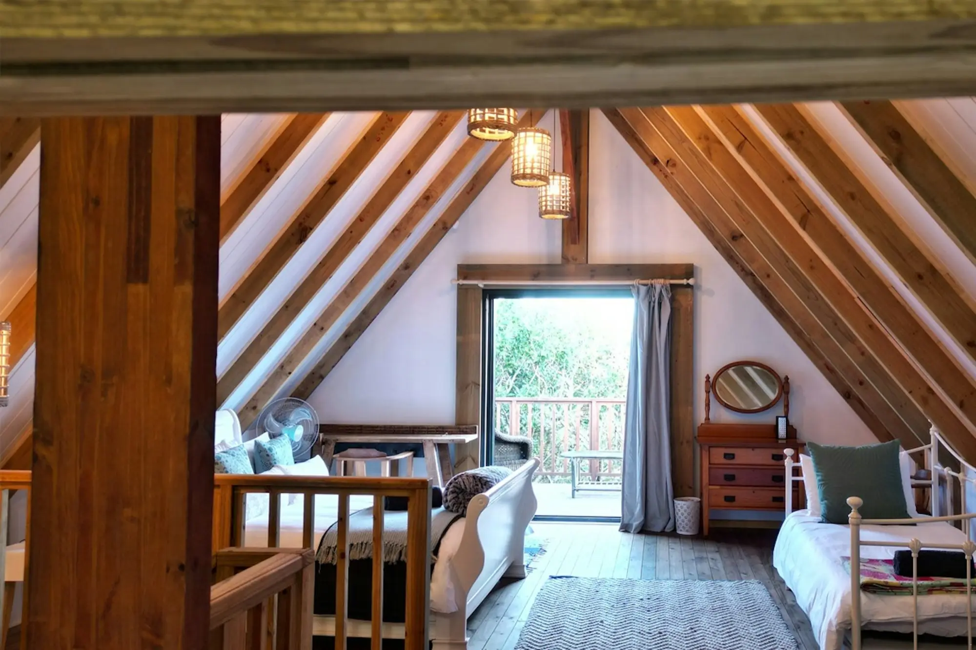 Wide view of the loft with beds, a sitting area and doors onto a balcony