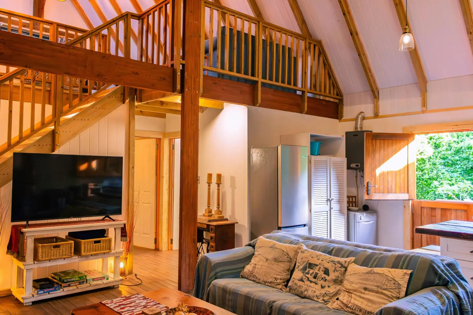 Living room with television and sofa, and the loft balustrade overhead